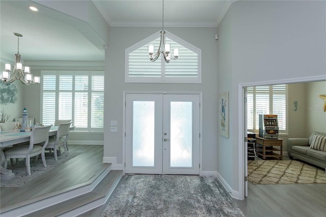 foyer with a chandelier, wood finished floors, baseboards, french doors, and ornamental molding
