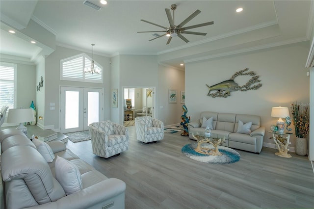 living room featuring a chandelier, wood finished floors, baseboards, a ceiling fan, and ornamental molding