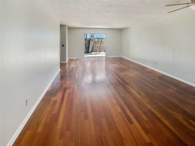 spare room featuring ceiling fan, dark wood-type flooring, and a textured ceiling