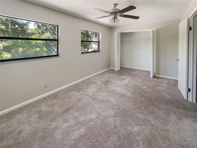 unfurnished bedroom with carpet flooring, a textured ceiling, a closet, and ceiling fan