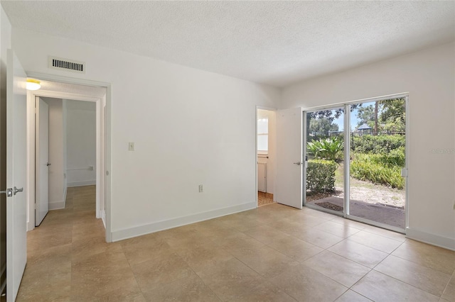 unfurnished room with light tile patterned floors and a textured ceiling