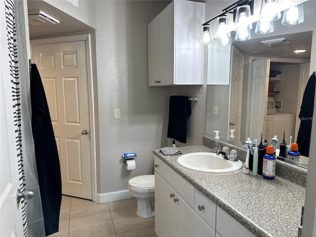 bathroom featuring independent washer and dryer, oversized vanity, tile flooring, and toilet