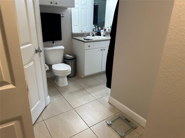 bathroom featuring tile floors, vanity, and toilet