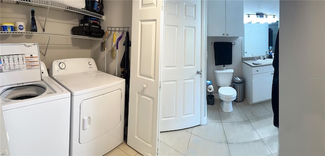 clothes washing area with washer and dryer, sink, and light tile floors