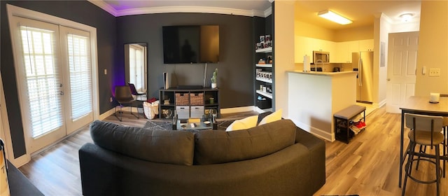 living room featuring light hardwood / wood-style floors, french doors, a healthy amount of sunlight, and crown molding