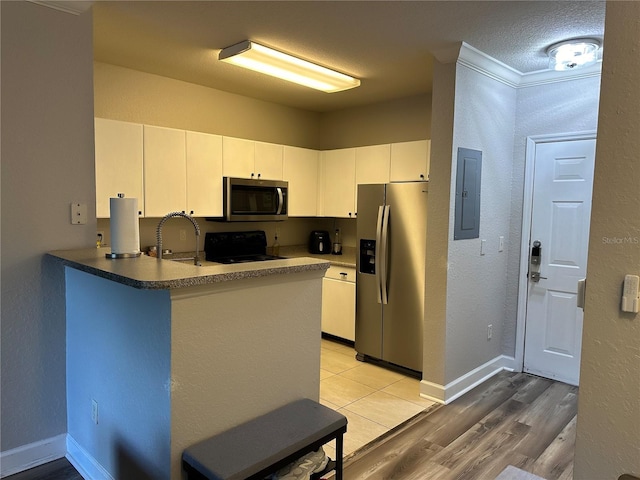 kitchen with kitchen peninsula, stainless steel appliances, ornamental molding, white cabinets, and light tile floors