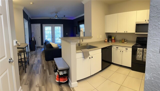 kitchen featuring light wood-type flooring, black appliances, kitchen peninsula, sink, and ceiling fan