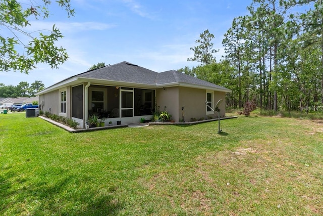 rear view of house with a lawn, central AC unit, and a sunroom