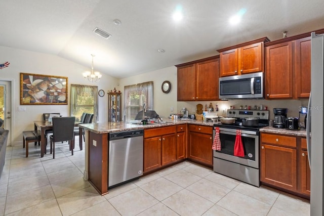 kitchen with appliances with stainless steel finishes, kitchen peninsula, a chandelier, and lofted ceiling