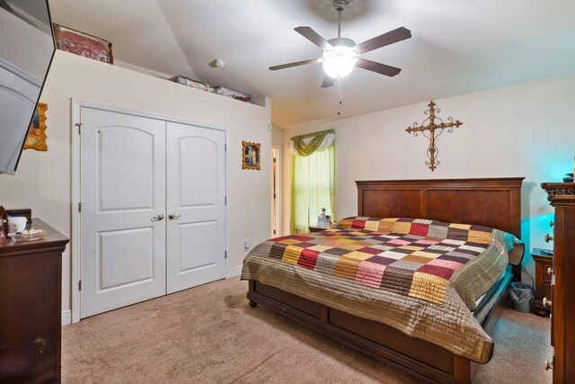 bedroom featuring vaulted ceiling, ceiling fan, a closet, and light colored carpet