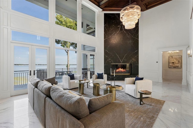 living room featuring plenty of natural light, a water view, and a towering ceiling