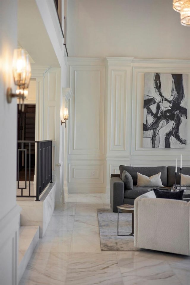 living area featuring a high ceiling, marble finish floor, and a decorative wall