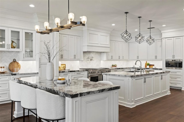 9832 Laurel Valley Dr, Windermere, FL 34786 - kitchen with double oven range, a center island with sink, tasteful backsplash, white cabinetry, and a chandelier