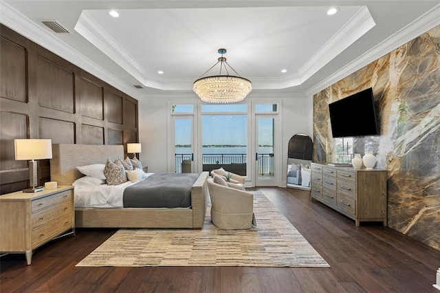 bedroom featuring a raised ceiling, access to exterior, dark hardwood / wood-style flooring, and ornamental molding