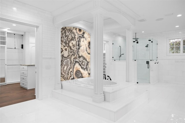 interior space with crown molding, hardwood / wood-style flooring, separate shower and tub, ornate columns, and tile walls