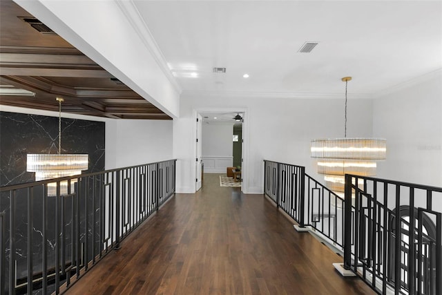 hallway featuring visible vents, wood finished floors, a notable chandelier, and ornamental molding