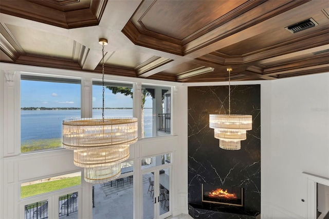 sunroom with visible vents, coffered ceiling, a high end fireplace, a water view, and a notable chandelier