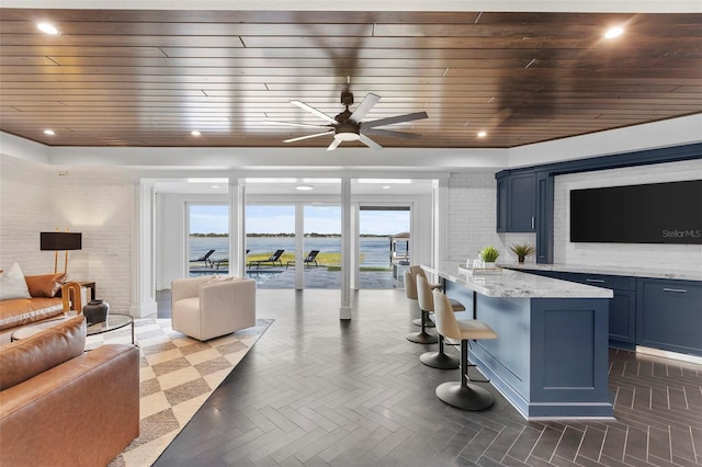 interior space featuring light stone countertops, dark parquet flooring, ceiling fan, blue cabinetry, and wooden ceiling