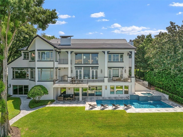 back of house featuring stucco siding, a chimney, a yard, a balcony, and a patio