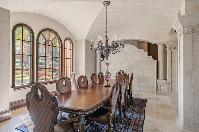 dining area featuring a chandelier, vaulted ceiling, and ornate columns