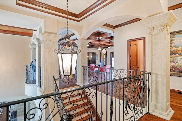 hall with beam ceiling, ornate columns, ornamental molding, a chandelier, and hardwood / wood-style flooring