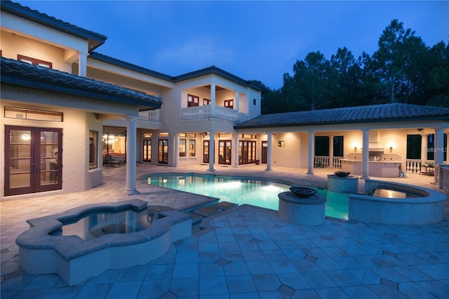 pool at dusk featuring a patio area, an in ground hot tub, and area for grilling