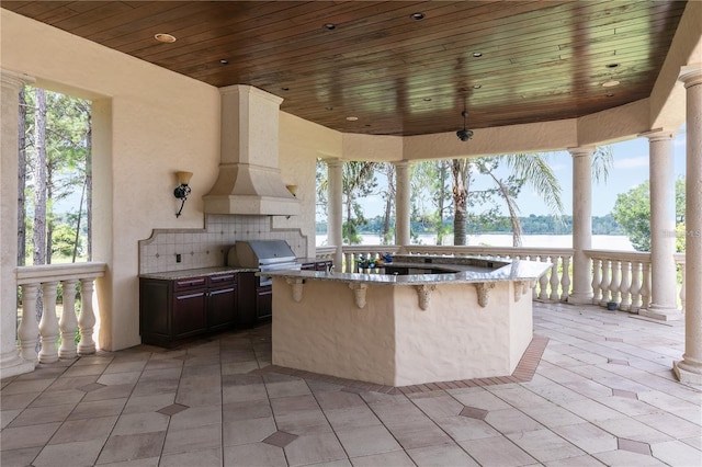 view of patio / terrace featuring an outdoor kitchen, a grill, and a water view