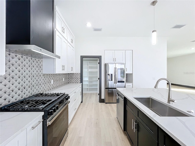 kitchen with light stone counters, pendant lighting, stainless steel appliances, and sink