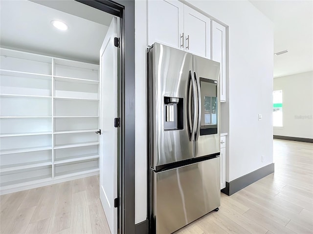 kitchen featuring white cabinets, stainless steel fridge, and light hardwood / wood-style floors