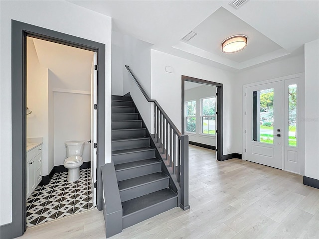 foyer with a tray ceiling and light wood-type flooring