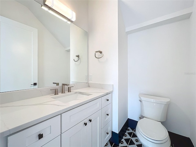 bathroom featuring vanity, toilet, and vaulted ceiling