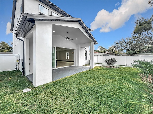 rear view of property featuring ceiling fan, a yard, and a patio