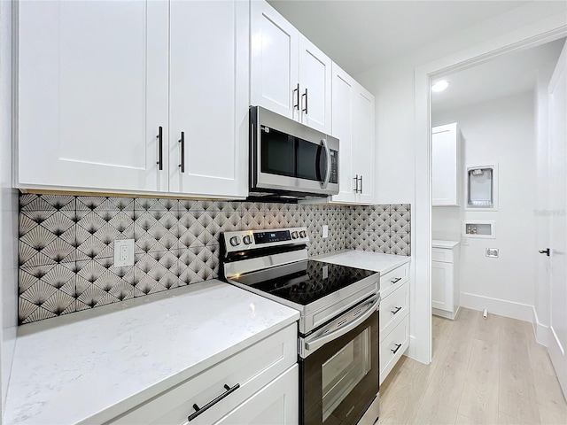 kitchen featuring light stone counters, light hardwood / wood-style floors, decorative backsplash, white cabinets, and appliances with stainless steel finishes