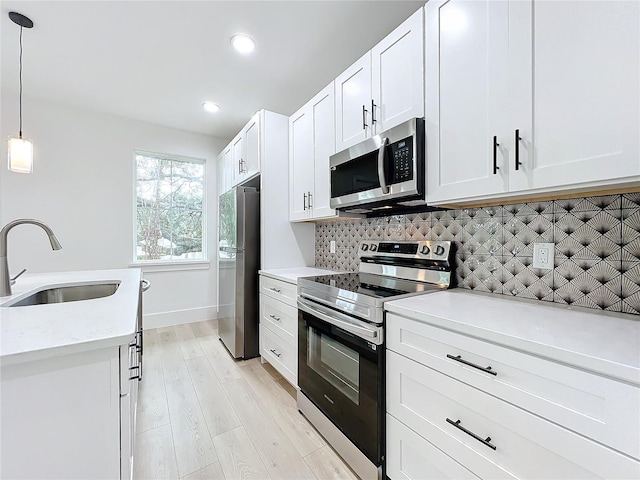 kitchen with pendant lighting, sink, white cabinets, and stainless steel appliances