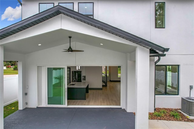 doorway to property featuring ceiling fan, central air condition unit, and sink