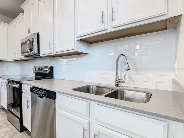 kitchen featuring white cabinets, backsplash, appliances with stainless steel finishes, light stone countertops, and sink