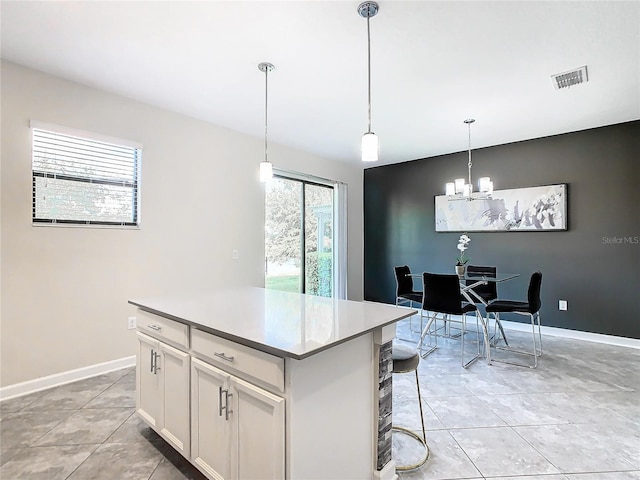 kitchen with a center island, white cabinetry, a healthy amount of sunlight, and decorative light fixtures