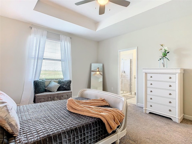 carpeted bedroom featuring ensuite bathroom, a raised ceiling, and ceiling fan