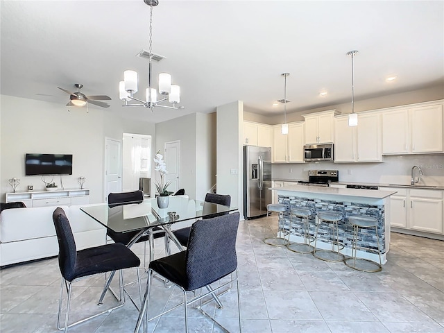 dining space with sink, ceiling fan with notable chandelier, and light tile patterned floors