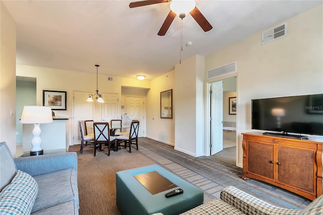 carpeted living room featuring ceiling fan with notable chandelier