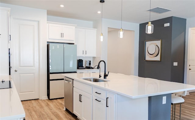 kitchen featuring white cabinetry, sink, decorative light fixtures, and a center island with sink