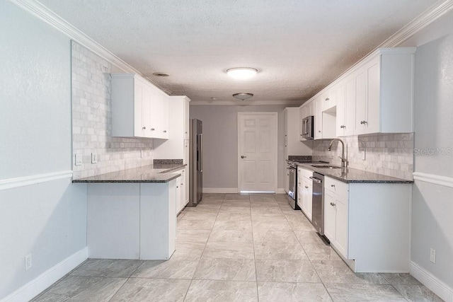 kitchen with white cabinets, stainless steel appliances, crown molding, and dark stone counters