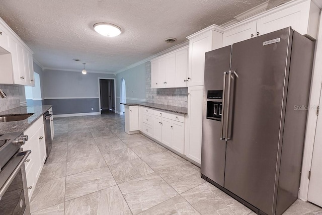 kitchen with white cabinetry, backsplash, appliances with stainless steel finishes, and dark stone counters