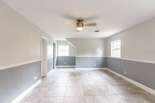 empty room with ceiling fan, plenty of natural light, and light tile patterned floors