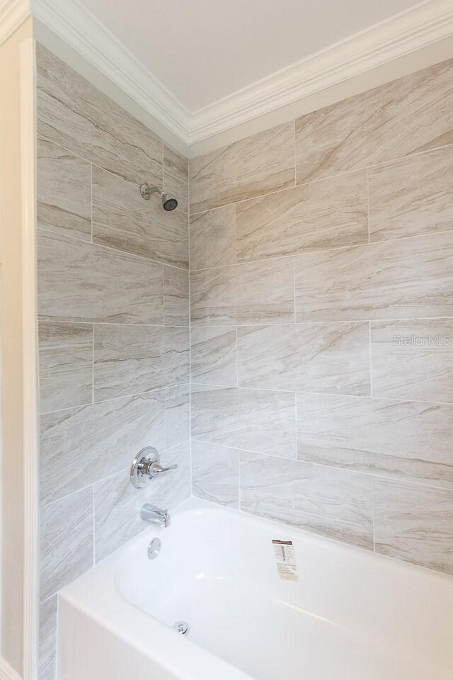 bathroom with tiled shower / bath combo and crown molding