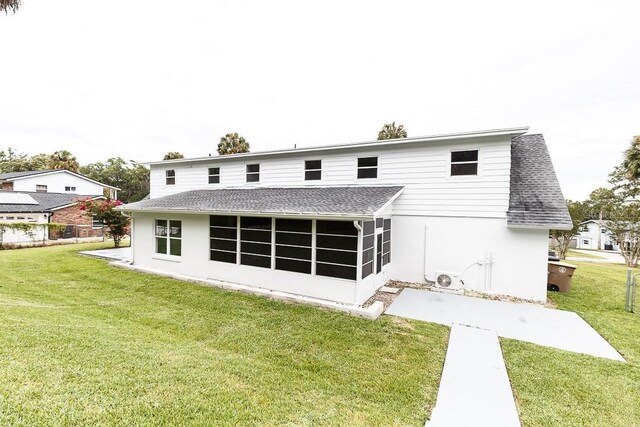 rear view of property featuring a lawn and a sunroom