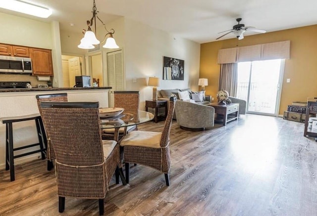 dining room with wood finished floors and ceiling fan with notable chandelier