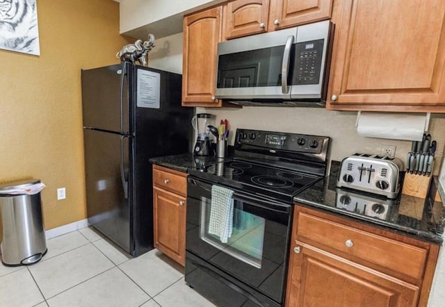 kitchen with brown cabinets, black appliances, and dark stone counters