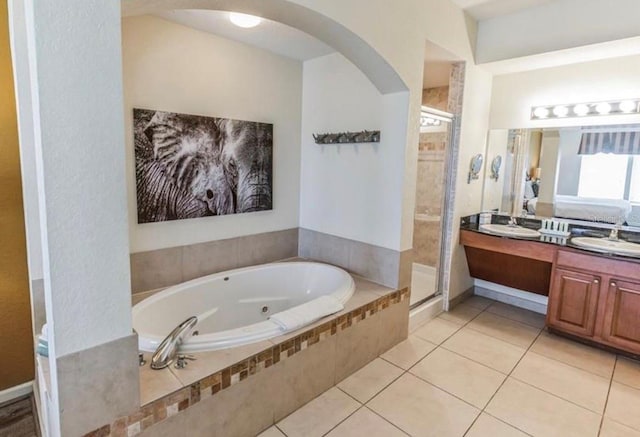 full bath featuring double vanity, a sink, a shower stall, a bath, and tile patterned floors