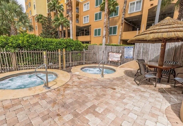 view of pool with a community hot tub, a patio area, and fence